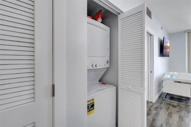 clothes washing area featuring stacked washing maching and dryer and light hardwood / wood-style floors