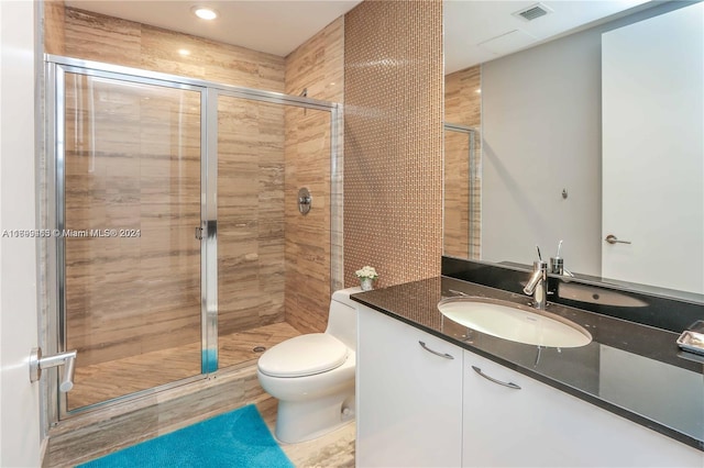 bathroom featuring wood-type flooring, vanity, toilet, and a shower with shower door