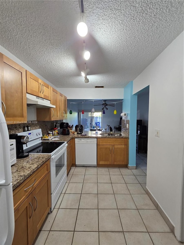 kitchen with a textured ceiling, white appliances, sink, light tile patterned floors, and stone countertops