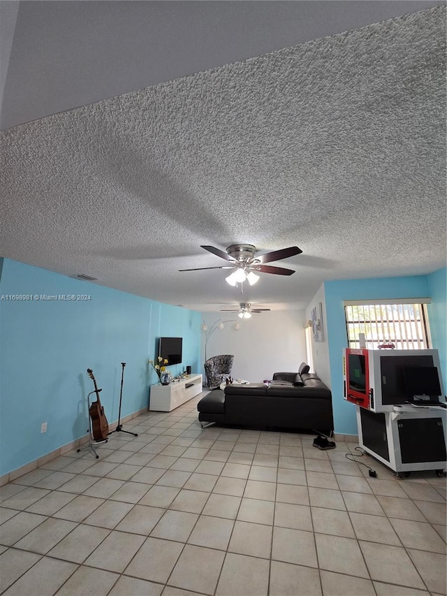 living room featuring ceiling fan, light tile patterned floors, and a textured ceiling