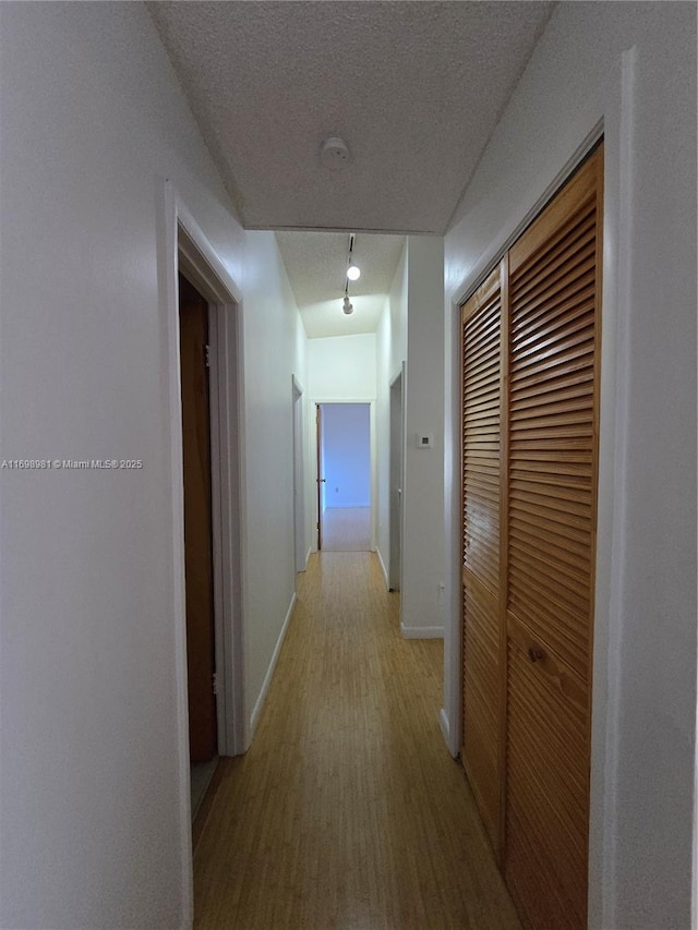 hall featuring light hardwood / wood-style floors and a textured ceiling