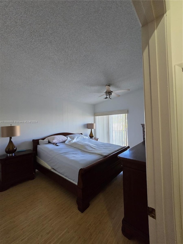 bedroom with a textured ceiling, dark hardwood / wood-style flooring, and ceiling fan