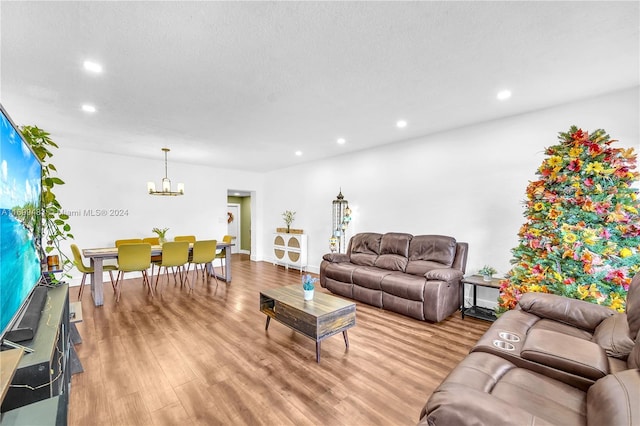 living room featuring light hardwood / wood-style flooring, a chandelier, and a textured ceiling