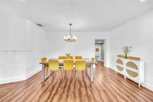 dining space featuring an inviting chandelier, a textured ceiling, and light hardwood / wood-style flooring