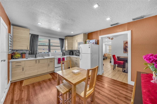 kitchen featuring a textured ceiling, white appliances, and light hardwood / wood-style floors