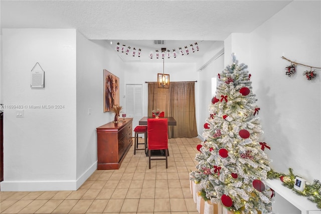 corridor with a chandelier, a textured ceiling, and light tile patterned flooring