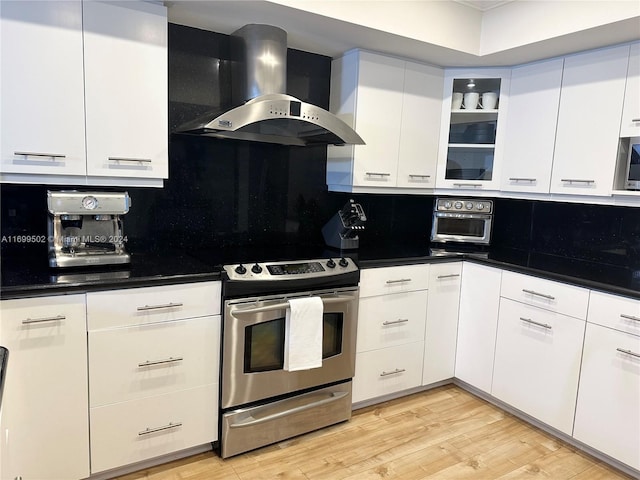 kitchen with white cabinets, light hardwood / wood-style flooring, stainless steel electric stove, and wall chimney range hood