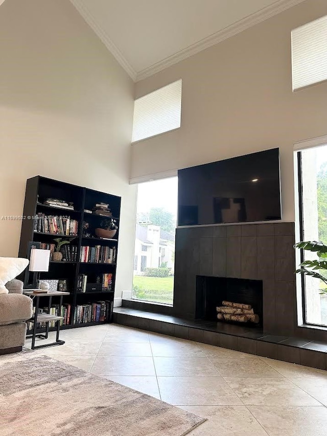 interior space with a tile fireplace, a towering ceiling, and ornamental molding