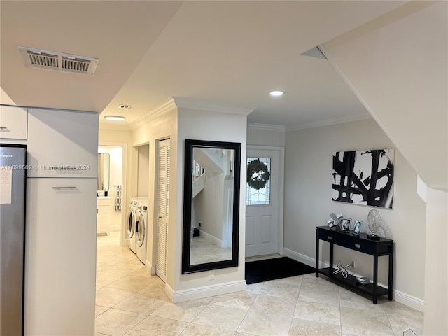 tiled entrance foyer with ornamental molding and independent washer and dryer