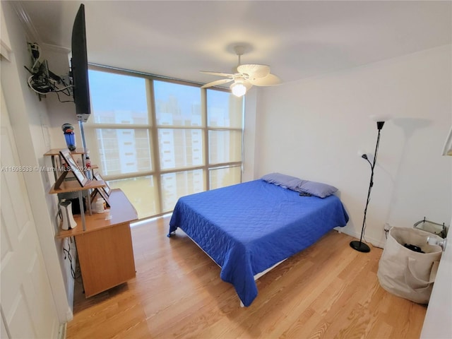 bedroom featuring ceiling fan, a wall of windows, and light hardwood / wood-style flooring