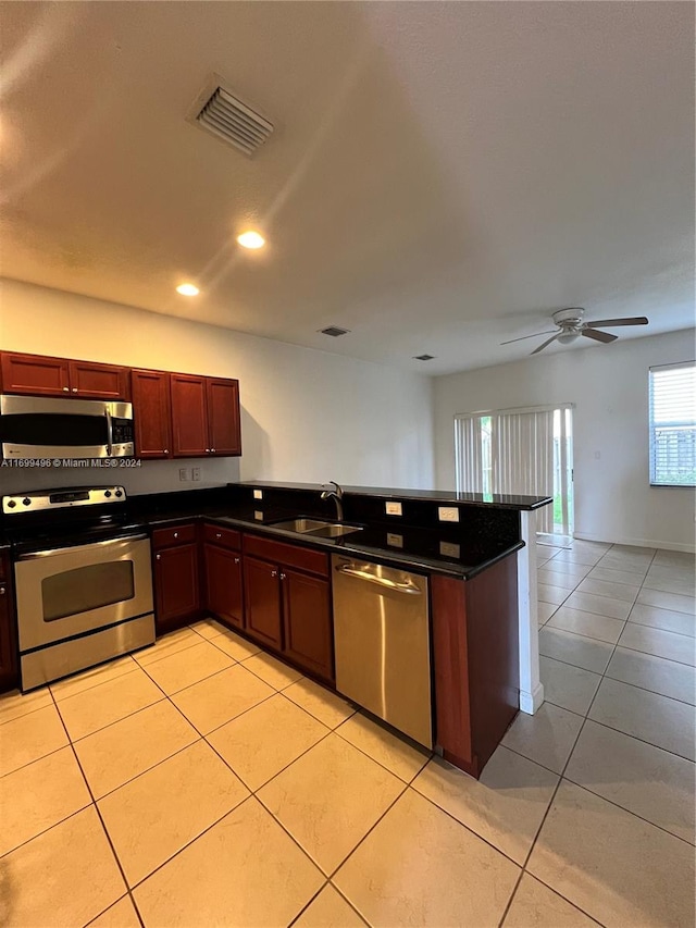 kitchen with appliances with stainless steel finishes, light tile patterned floors, ceiling fan, and sink