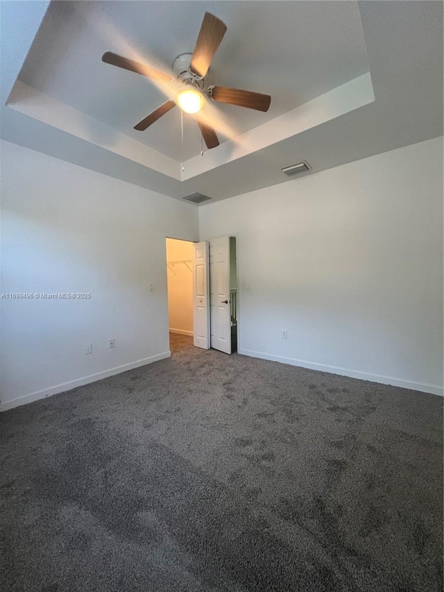 carpeted empty room featuring ceiling fan and a tray ceiling