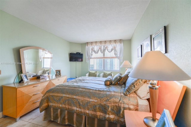 bedroom with multiple windows, light tile patterned floors, and a textured ceiling