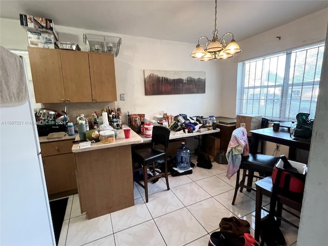 kitchen featuring pendant lighting, light tile patterned flooring, kitchen peninsula, and an inviting chandelier