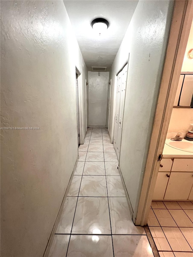 hall featuring sink and light tile patterned flooring