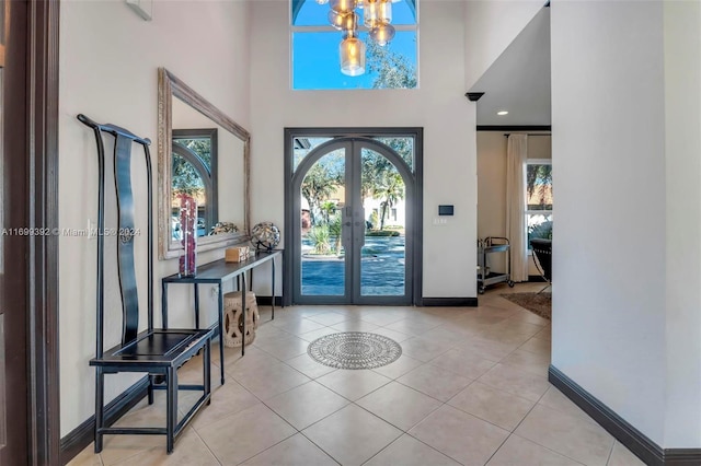 entryway with a chandelier, french doors, light tile patterned floors, and a high ceiling