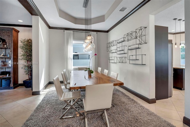 dining room with light tile patterned floors, a raised ceiling, and ornamental molding