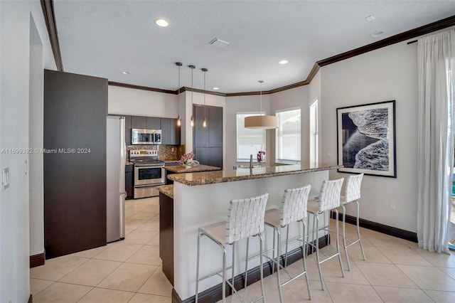 kitchen with a kitchen breakfast bar, hanging light fixtures, light tile patterned floors, appliances with stainless steel finishes, and tasteful backsplash