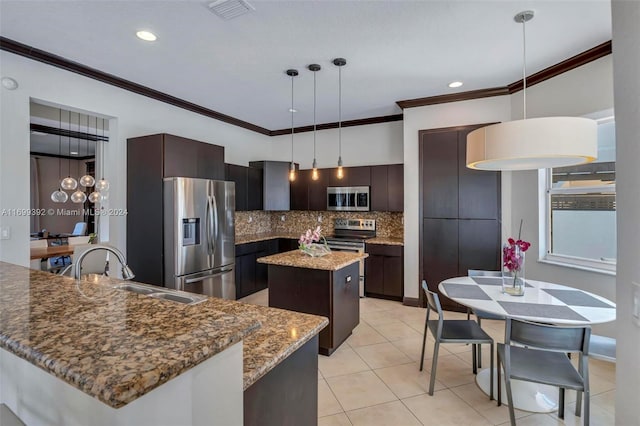 kitchen featuring backsplash, dark brown cabinets, stainless steel appliances, decorative light fixtures, and a kitchen island