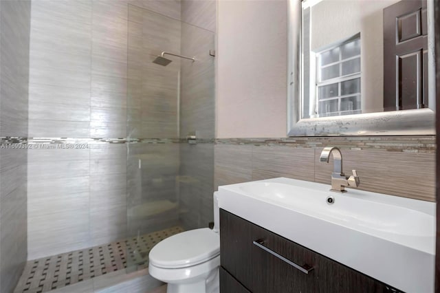 bathroom featuring vanity, toilet, tile walls, and a tile shower