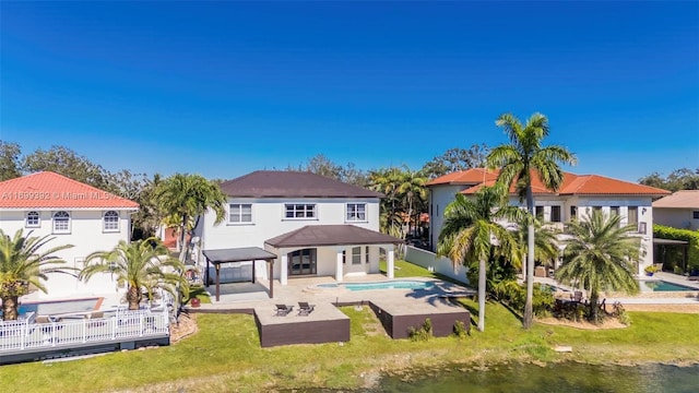 back of house with a lawn, a water view, and a patio