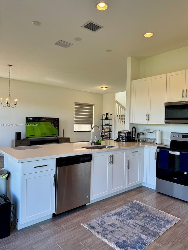 kitchen featuring pendant lighting, stainless steel appliances, and white cabinetry