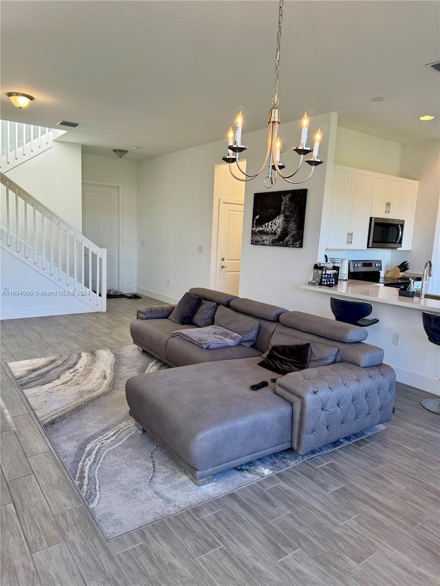 living room with light hardwood / wood-style flooring, an inviting chandelier, and sink