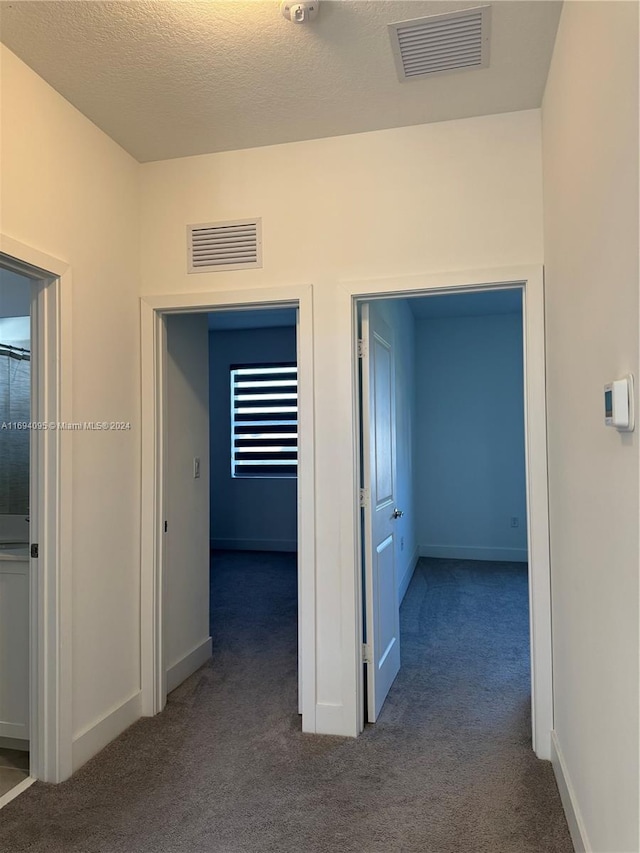 hall with carpet flooring and a textured ceiling