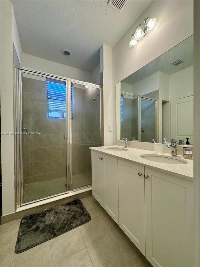 bathroom with tile patterned flooring, vanity, a textured ceiling, and a shower with shower door