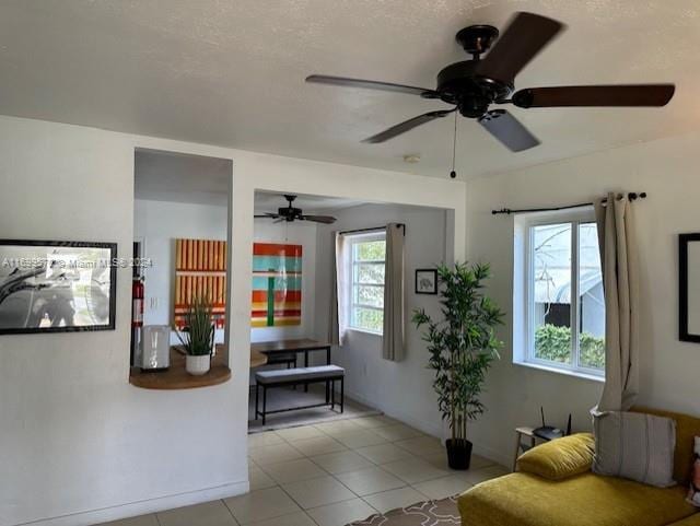 living room featuring ceiling fan, light tile patterned floors, a textured ceiling, and a wealth of natural light