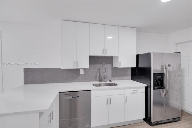 kitchen featuring sink, stainless steel appliances, tasteful backsplash, light hardwood / wood-style flooring, and white cabinets