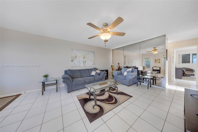 living room featuring ceiling fan, light tile patterned floors, and a textured ceiling