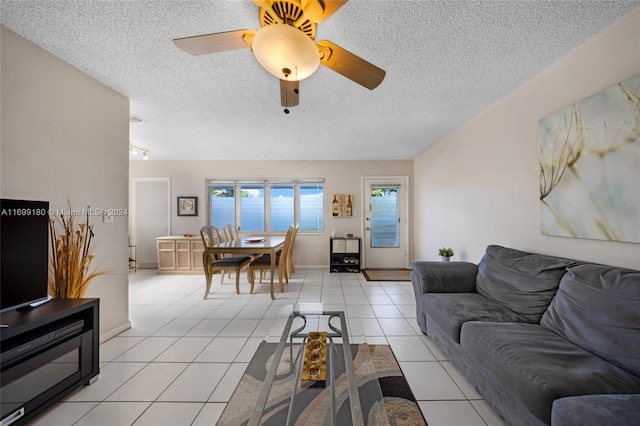 living room with ceiling fan, light tile patterned floors, and a textured ceiling