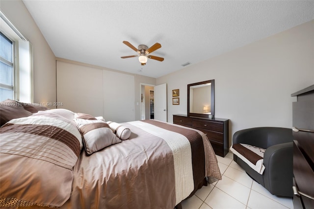 tiled bedroom with ceiling fan and a textured ceiling