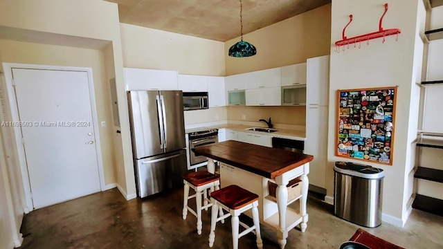 kitchen featuring white cabinets, a towering ceiling, sink, and appliances with stainless steel finishes