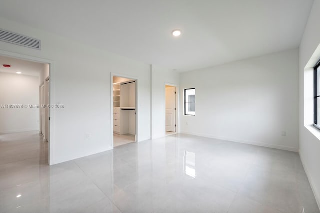 unfurnished bedroom with visible vents, a walk in closet, baseboards, recessed lighting, and a closet