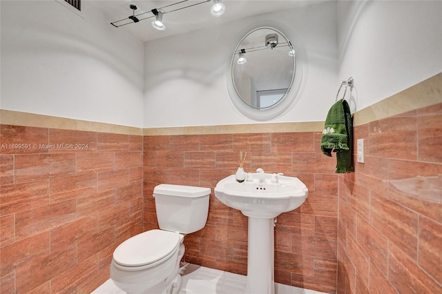 bathroom featuring toilet and tile walls