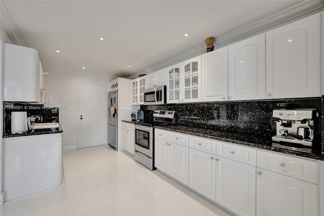 kitchen with decorative backsplash, stainless steel appliances, white cabinetry, and dark stone counters