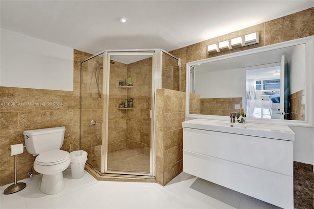 bathroom with tile patterned flooring, toilet, a shower with door, vanity, and tile walls