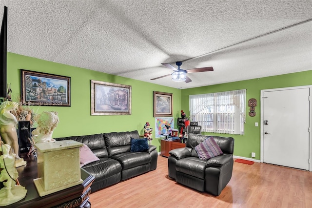 living room featuring ceiling fan, light hardwood / wood-style floors, and a textured ceiling