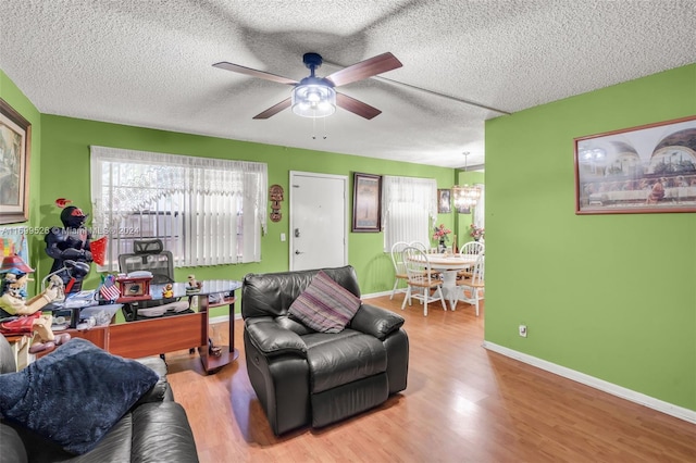 living room with ceiling fan with notable chandelier, hardwood / wood-style floors, and a textured ceiling