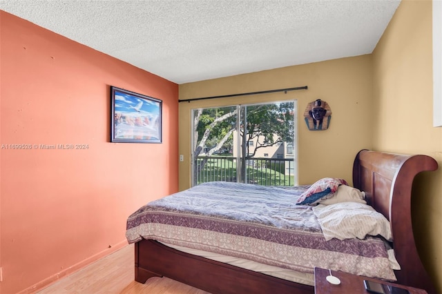 bedroom featuring access to exterior, light wood-type flooring, and a textured ceiling