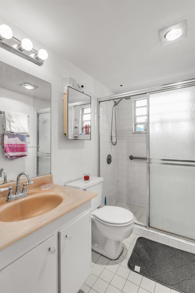 bathroom featuring tile patterned flooring, vanity, toilet, and an enclosed shower