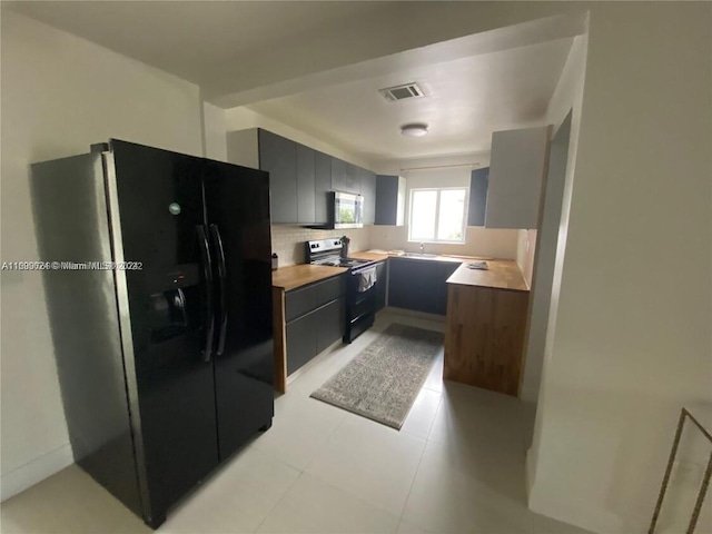 kitchen featuring tasteful backsplash, sink, light tile patterned floors, and stainless steel appliances