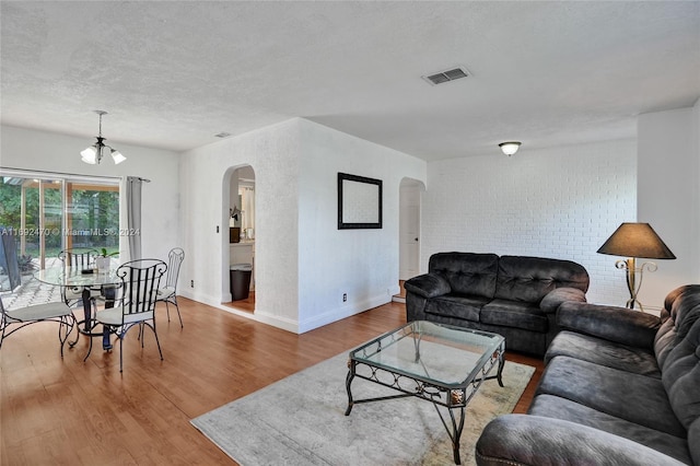 living room with hardwood / wood-style floors, a textured ceiling, and an inviting chandelier