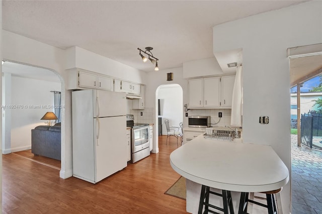 kitchen with backsplash, sink, light wood-type flooring, white cabinetry, and stainless steel appliances