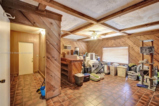 interior space with beam ceiling, wooden walls, ceiling fan, and a textured ceiling