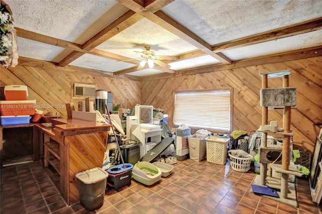 interior space featuring beam ceiling, wooden walls, ceiling fan, and a textured ceiling