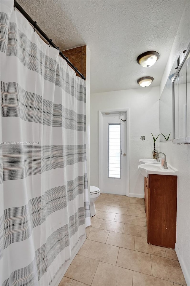 bathroom with tile patterned floors, a shower with curtain, vanity, a textured ceiling, and toilet