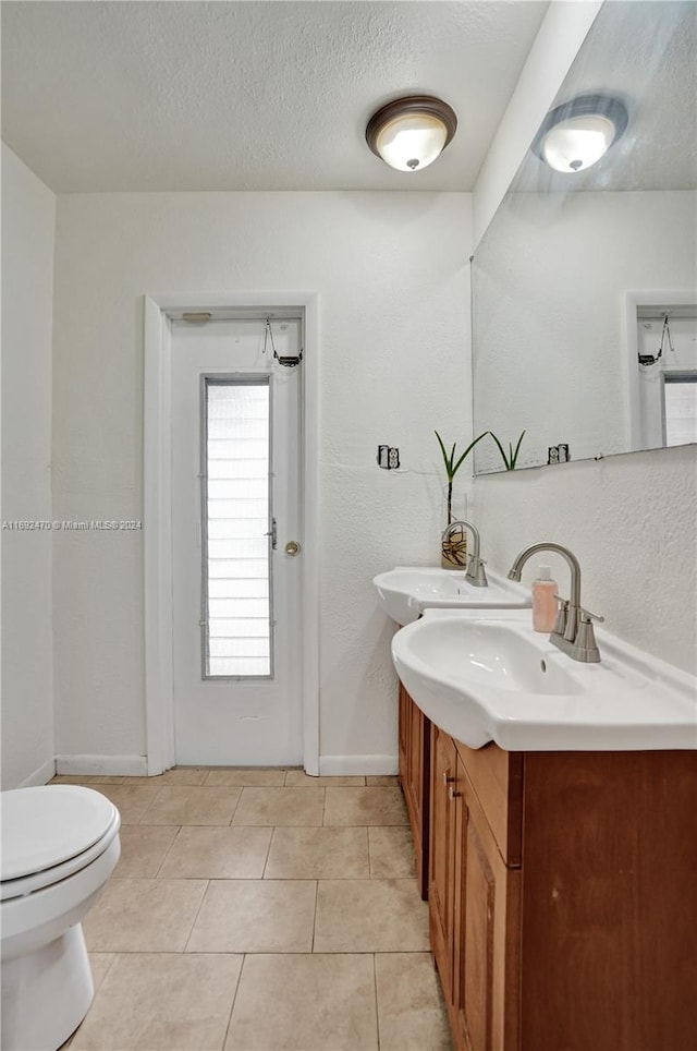 bathroom with tile patterned flooring, vanity, toilet, and a textured ceiling